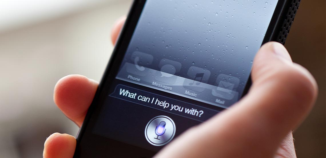Someone holding phone with Siri asking "what can I do for you?"
