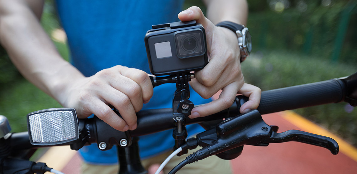 Someone attaching a GoPro to the handlebars on their bike