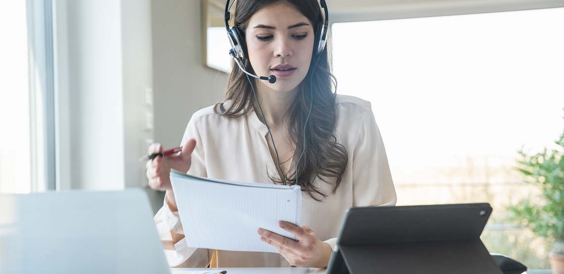 A woman with brown hair wearing a headset for a work conference call.