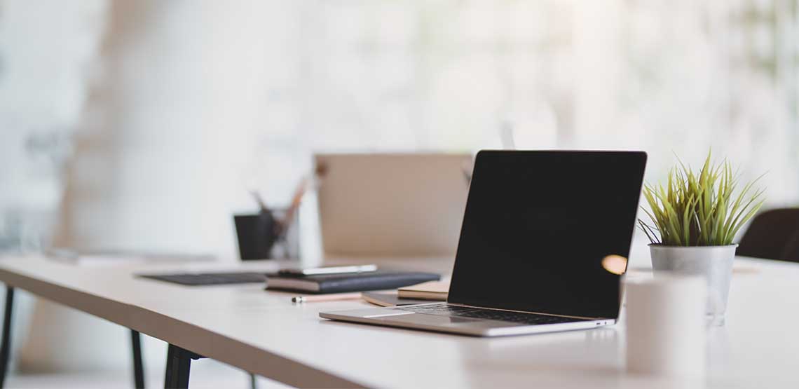An opened, turned off laptop sitting on a wooden table.