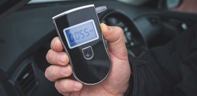 A person holding a black breathalyzer.