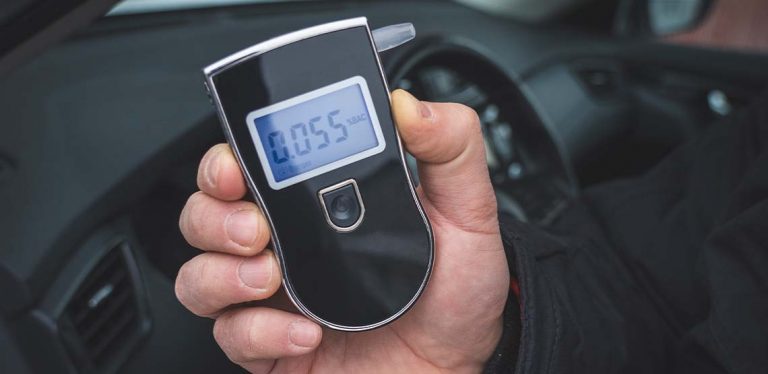 A person holding a black breathalyzer.