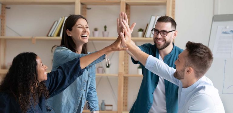 Four co-workers high-fiving.