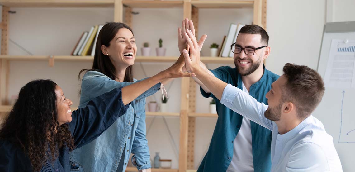 Four co-workers high-fiving.