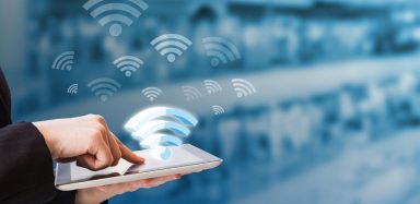 A person holding their finger on a tablet, with wifi signal icons floating above the screen.